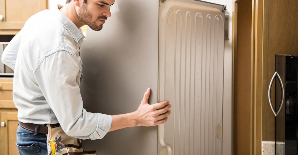 homem desencostando a geladeira para da parede para limpeza